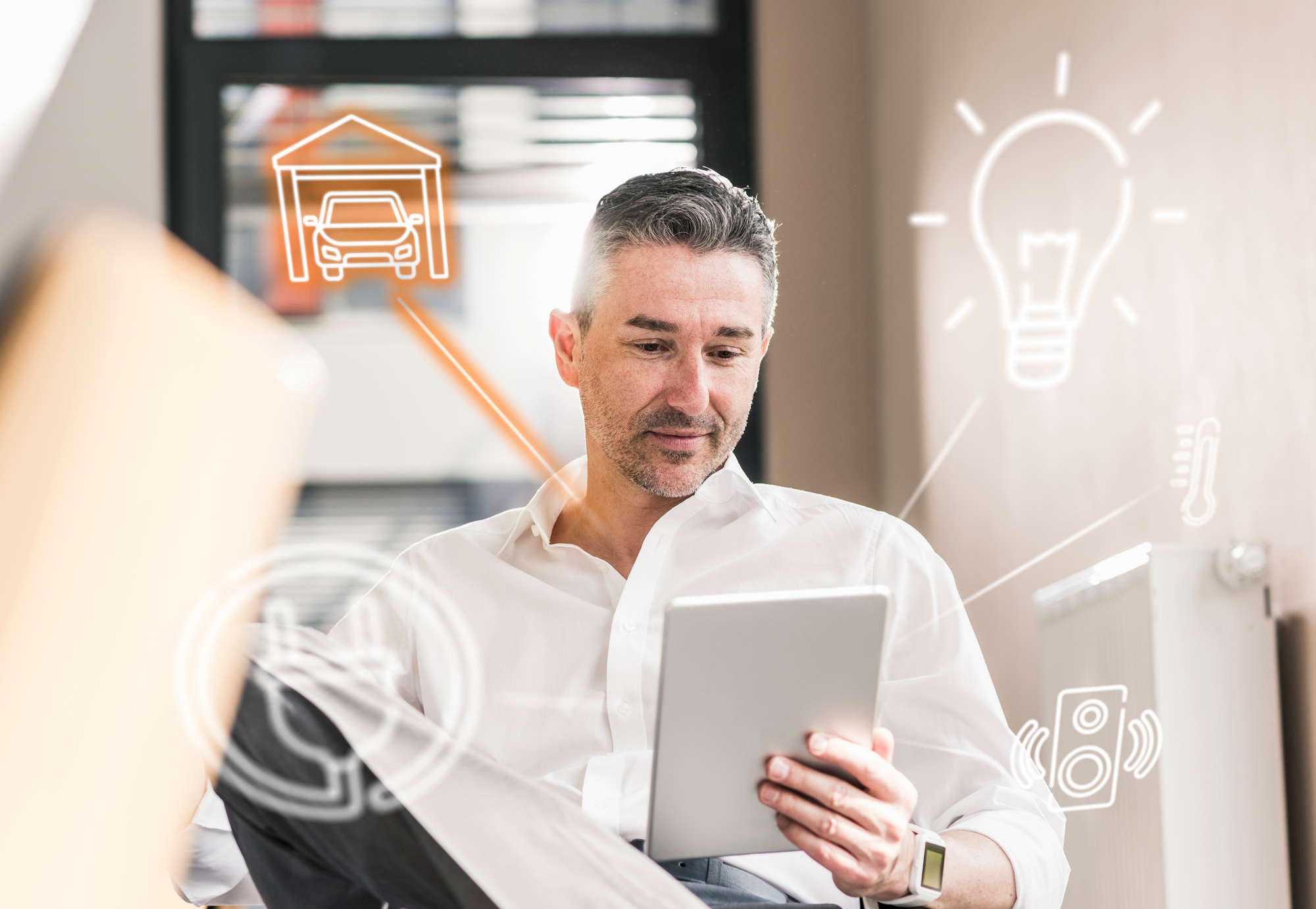 Man sitting in office, using digital tablet to remote-control his smart home