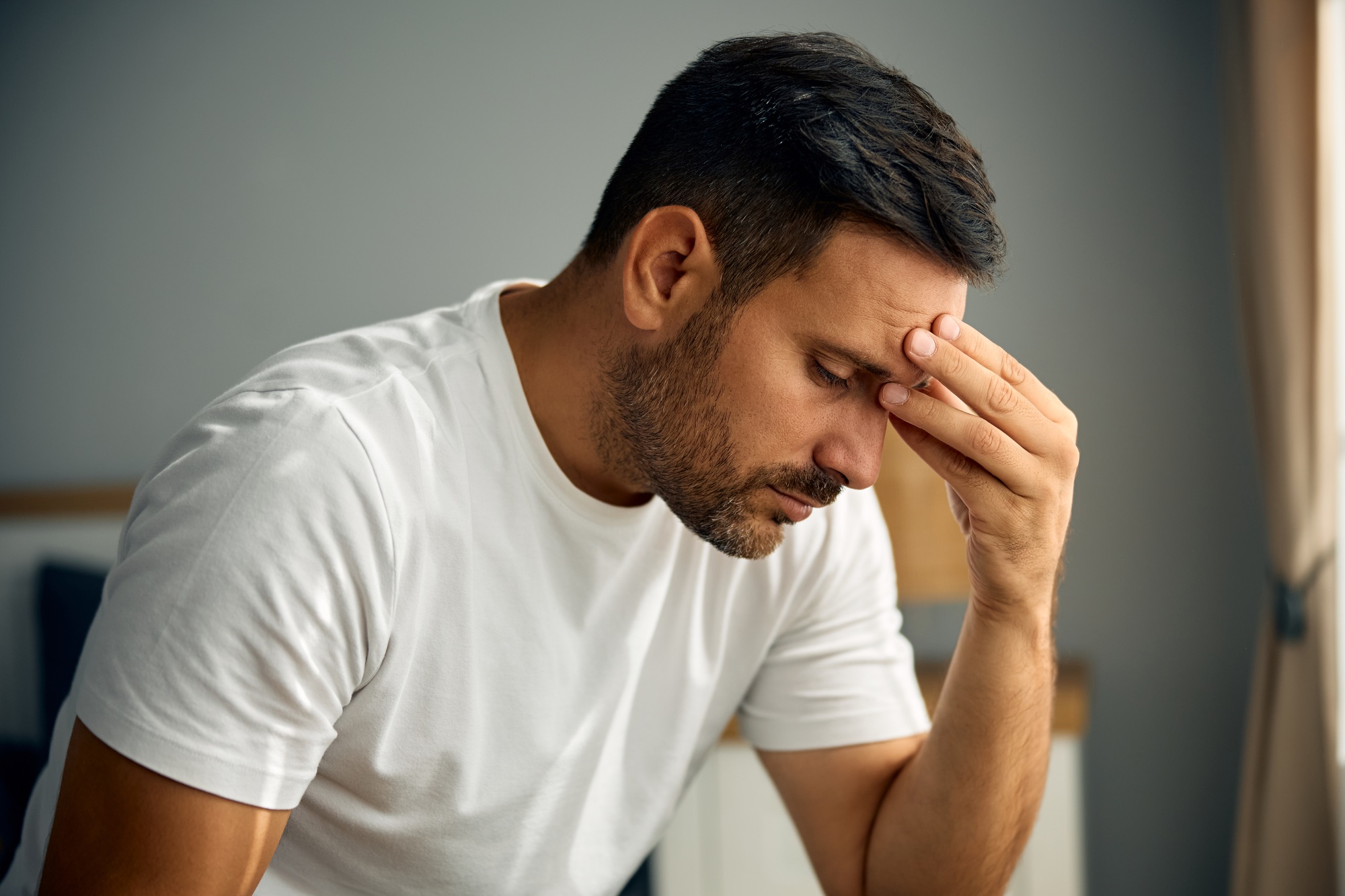 Stressed man holding his head in pain in the morning.