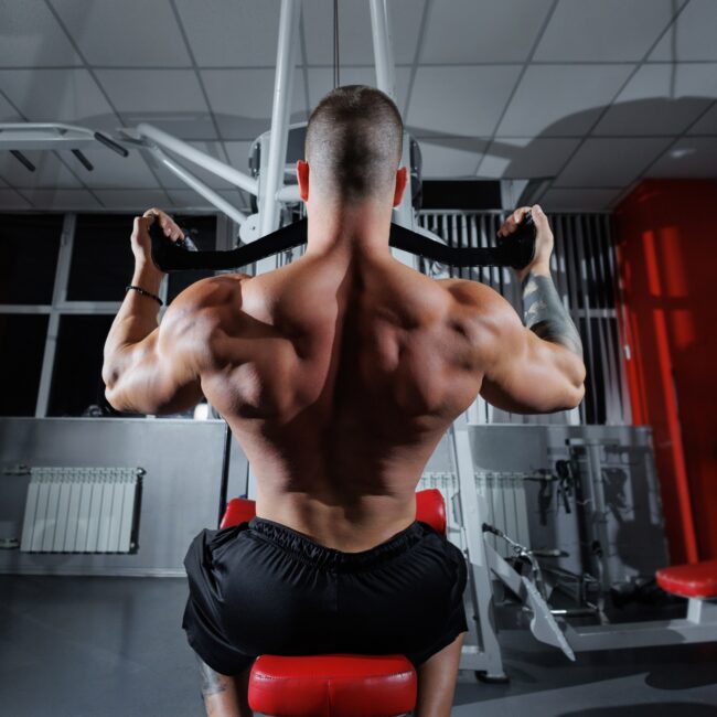 Training a strong man with big muscles, lifting weights on the machines in the gym.