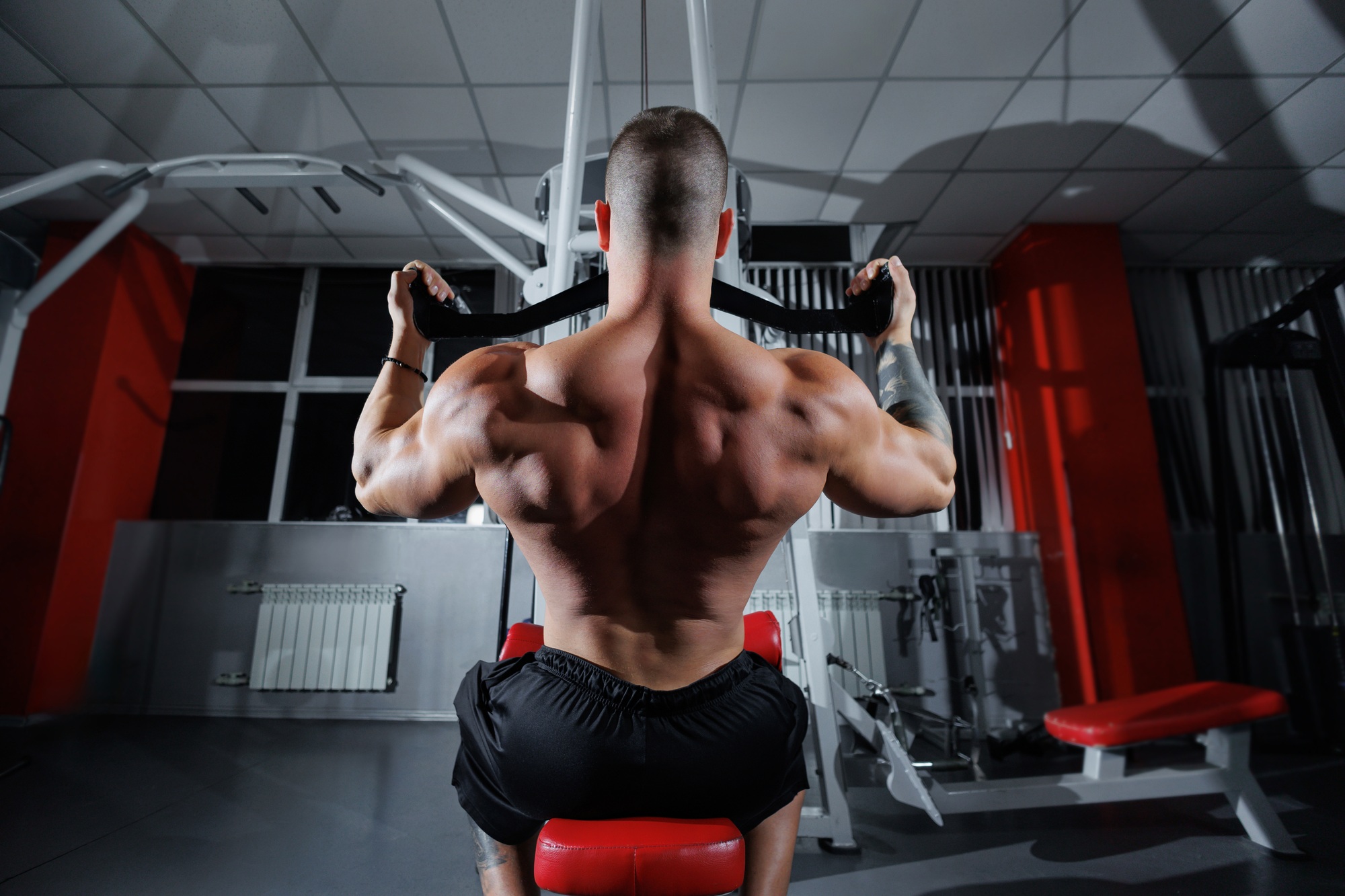 Training a strong man with big muscles, lifting weights on the machines in the gym.