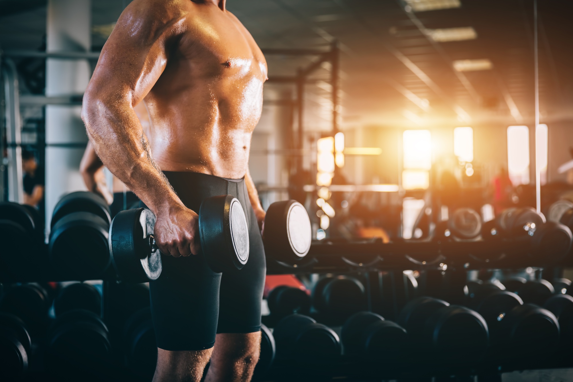 Muscular man holding dumbbels in a gym.