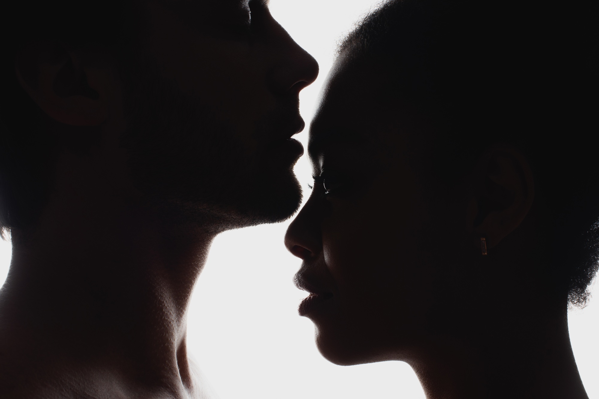 side view of silhouettes of interracial couple in love